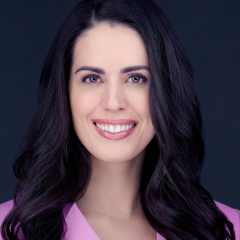 Female real estate agent with long dark hair, nice smile, pink jacket.