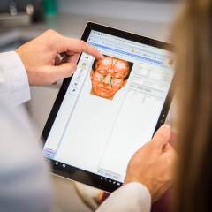 Plastic Surgeon Reviewing Surgery Plans On A Tablet Device Increases Patient Acceptance
